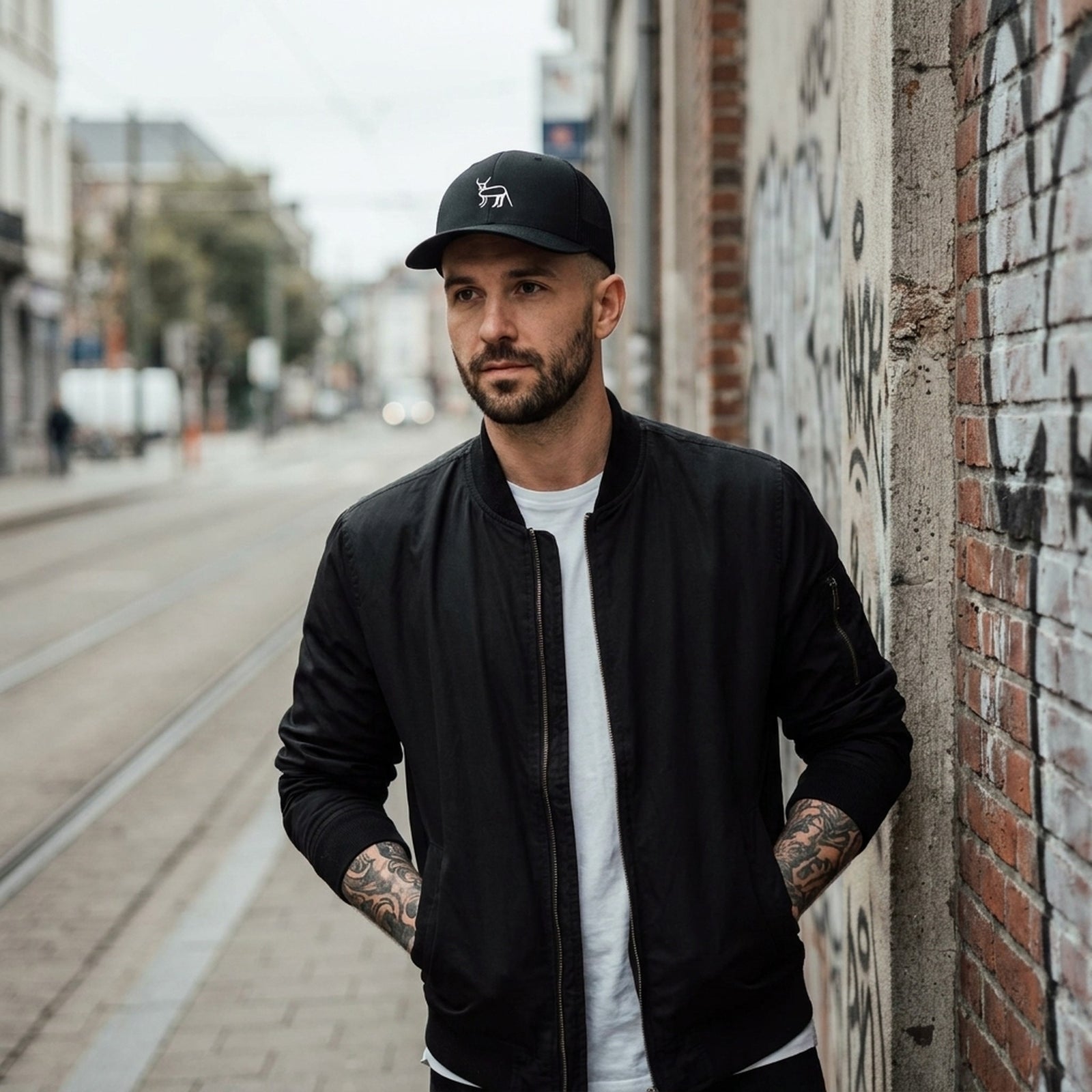 Homme en streetwear portant la casquette originale Coucou Petite Perruche dans une rue de Bruxelles