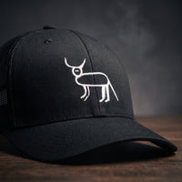 Gros plan sur la broderie blanche de la perruche ratée (animal à cornes) sur casquette trucker noire
