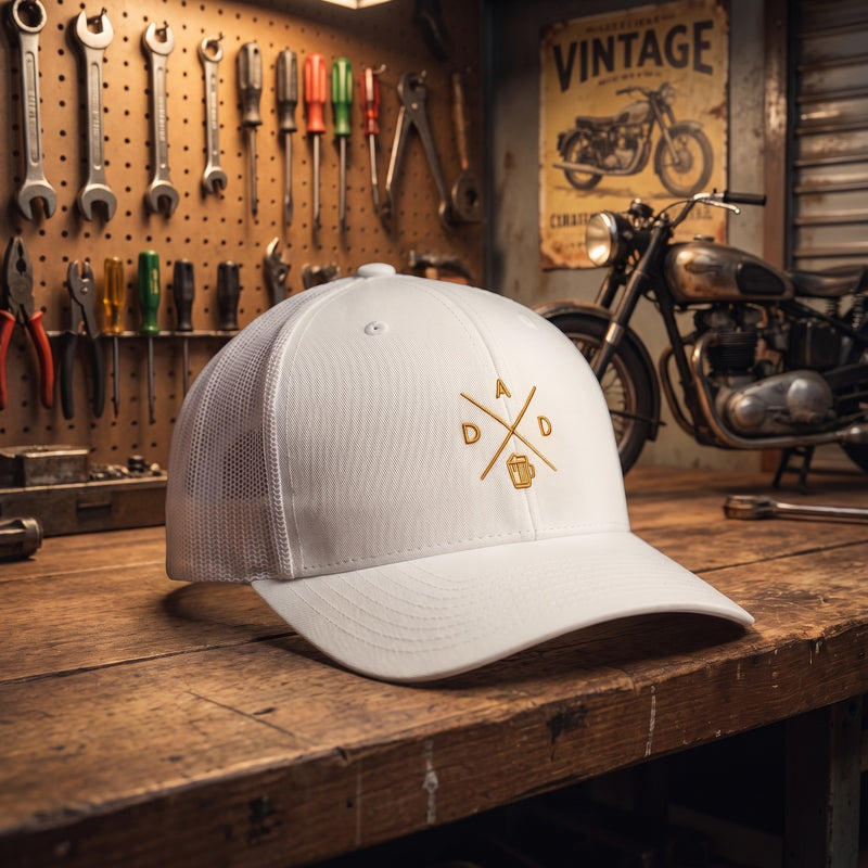 Casquette trucker brodée DAD dans un atelier de garage vintage avec outils et moto ancienne