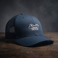 Casquette trucker Daddy Cool bleu marine, logo brodé, posée sur bois sombre