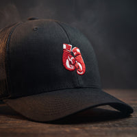 Gros plan sur la broderie en relief des gants de boxe rouges sur une casquette trucker noire