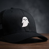 Gros plan sur le logo fantôme blanc brodé de la casquette trucker GHOST noire