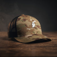 Casquette trucker GHOST camouflage multicam vert avec fantôme blanc brodé, filet noir, sur bois sombre