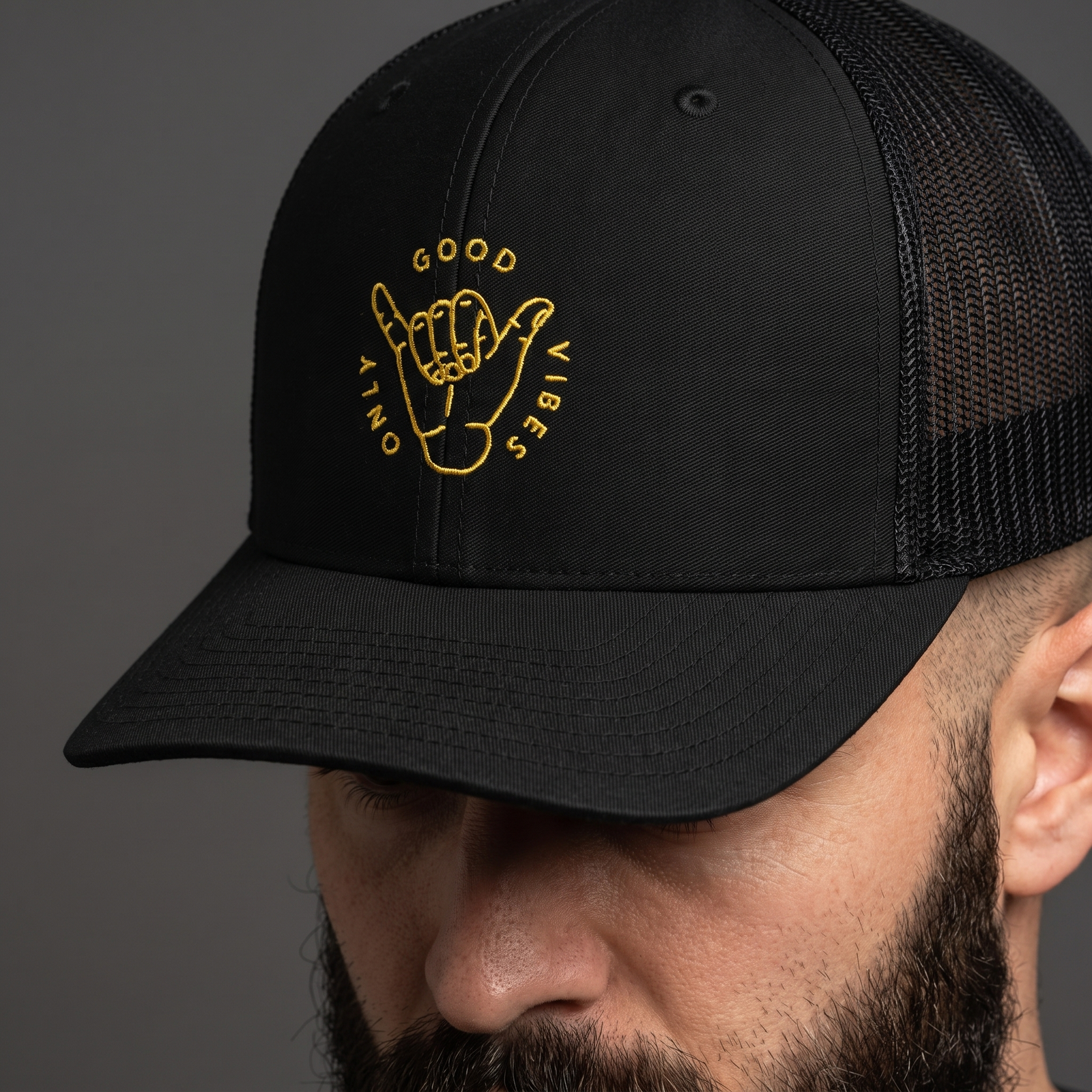 Gros plan sur la broderie shaka Good Vibes Only de la casquette trucker noire portée