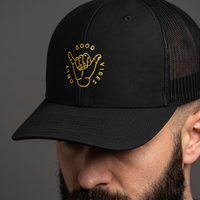 Gros plan sur la broderie shaka Good Vibes Only de la casquette trucker noire portée