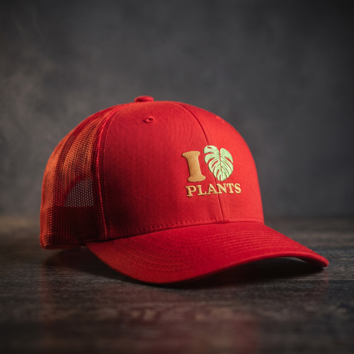 Casquette trucker rouge brodée I LOVE PLANTS avec cœur en feuille de monstera verte, vue trois quarts