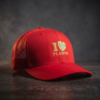 Casquette trucker rouge brodée I LOVE PLANTS avec cœur en feuille de monstera verte, vue trois quarts