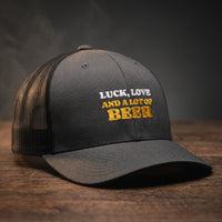 Casquette trucker anthracite avec filet noir brodée « Luck, Love and a lot of Beer » en blanc et jaune doré