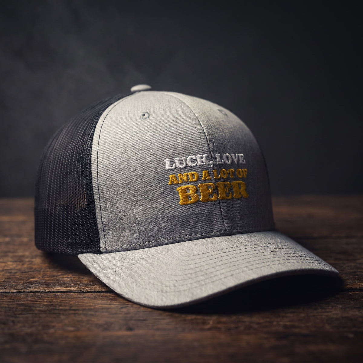 Casquette trucker gris chiné avec filet noir brodée « Luck, Love and a lot of Beer » en blanc et jaune doré