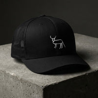 Casquette trucker noire brodée Coucou Petite Perruche vue de trois quarts sur béton