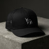 Casquette trucker noire brodée Coucou Petite Perruche vue de trois quarts sur béton
