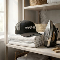Casquette trucker PROPRE posée sur du linge fraîchement plié à côté d'un fer à repasser vintage - CHT'M Boutique