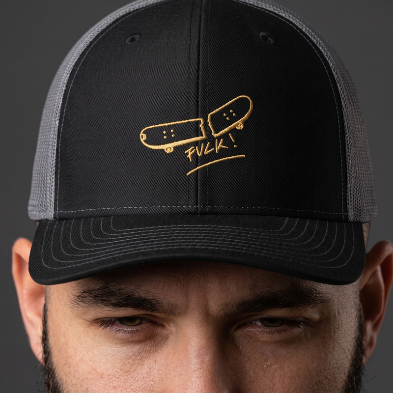 Zoom sur la broderie dorée planche de skate cassée de la casquette trucker
