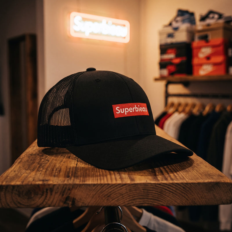 Casquette trucker noire Superbieau sur une étagère en bois dans une boutique streetwear