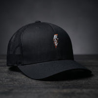 Casquette trucker Thunder Skull noire avec crâne et éclair brodés, filet noir, posée sur bois sombre