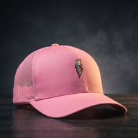 Casquette trucker Thunder Skull rose avec crâne et éclair brodés, posée sur bois sombre