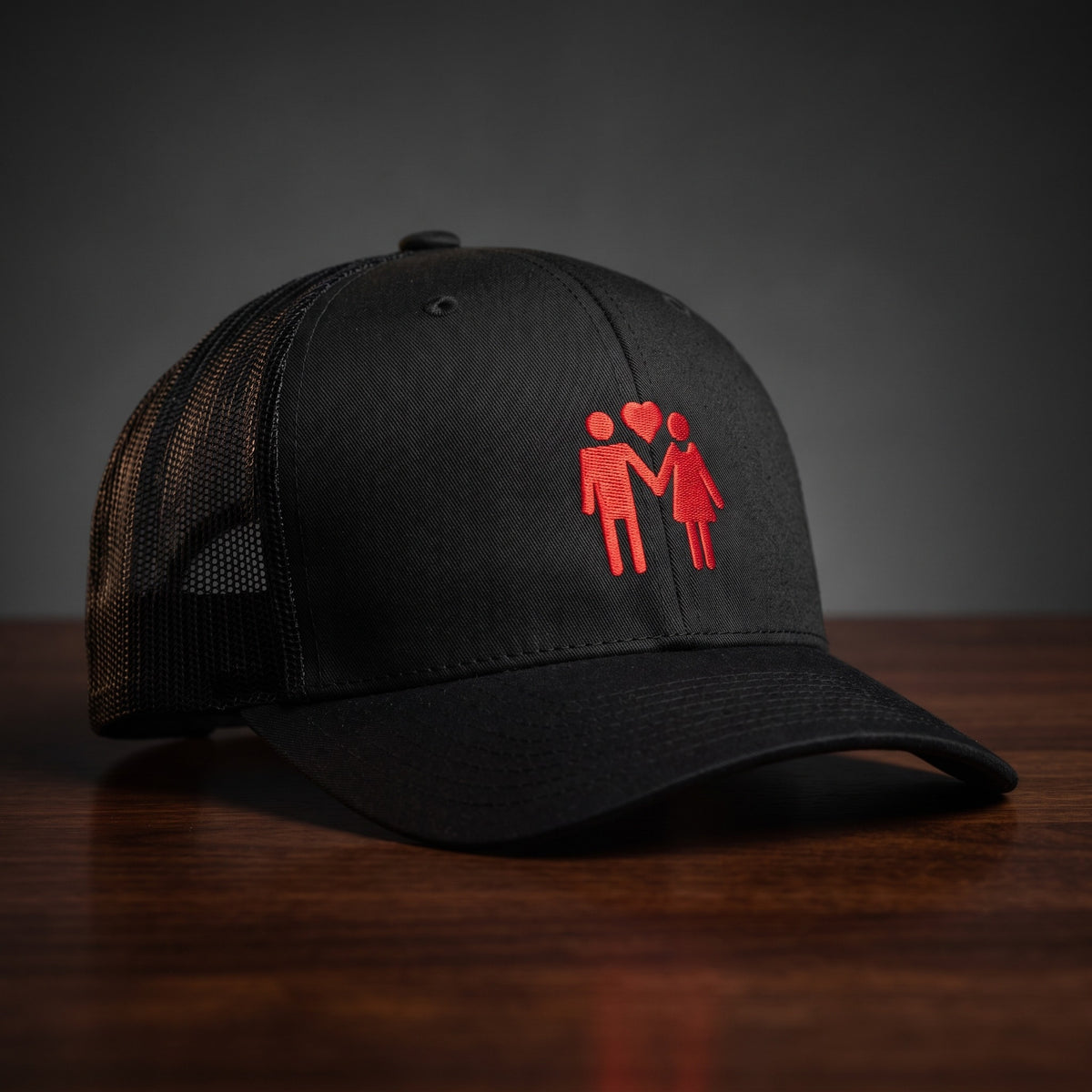 Casquette trucker brodée TOGETHER, noire, couple main dans la main sous un cœur brodé rouge, vue de face