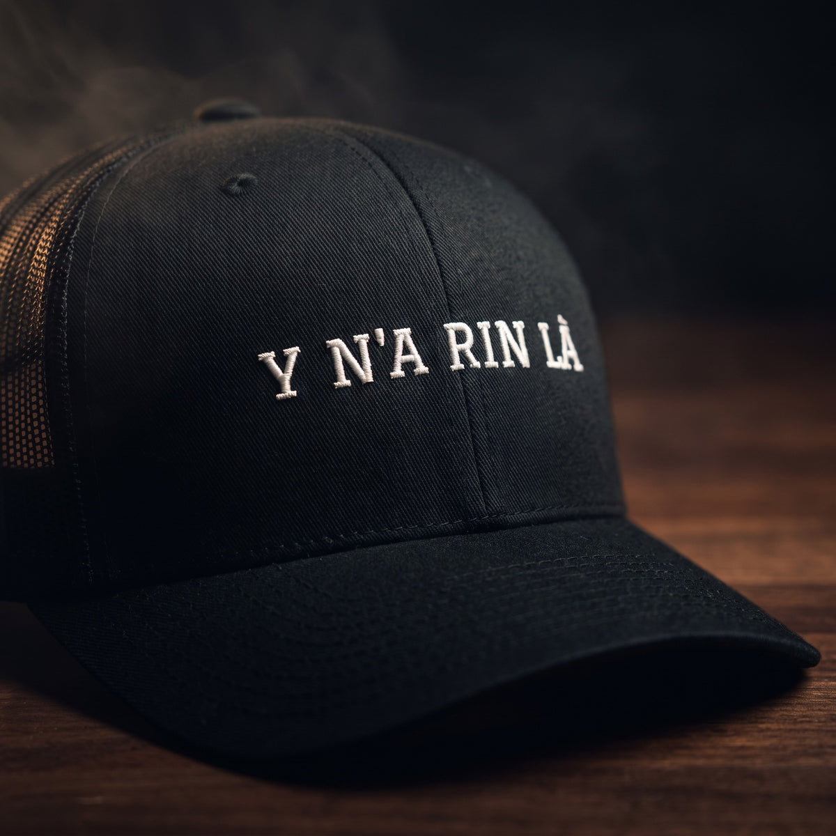 Gros plan sur la broderie blanche « Y N'A RIN LÀ » sur casquette trucker noire