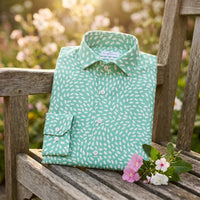 Chemise homme à manches longues vert menthe à petites touches blanches pliée sur un banc en bois dans un jardin fleuri - CHT'M Boutique