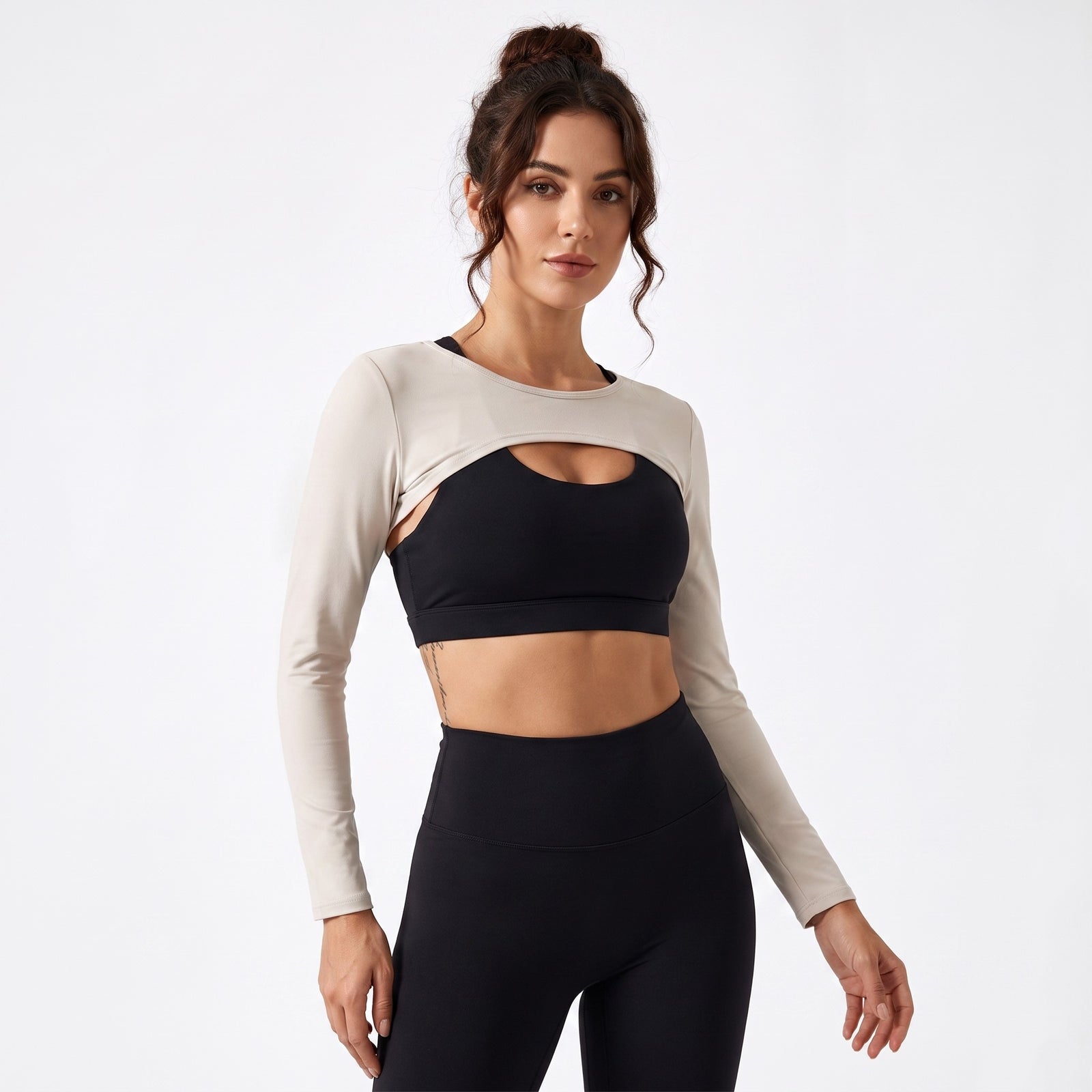 Femme portant le boléro de sport original beige sur brassière noire, photo studio