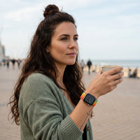 Bracelet Apple Watch en nylon motif peinture arc-en-ciel vif porté par une femme, look streetwear en Belgique | CHT'M Boutique