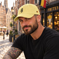 Casquette belge originale B gothique jaune portée par un homme dans une rue de Bruxelles