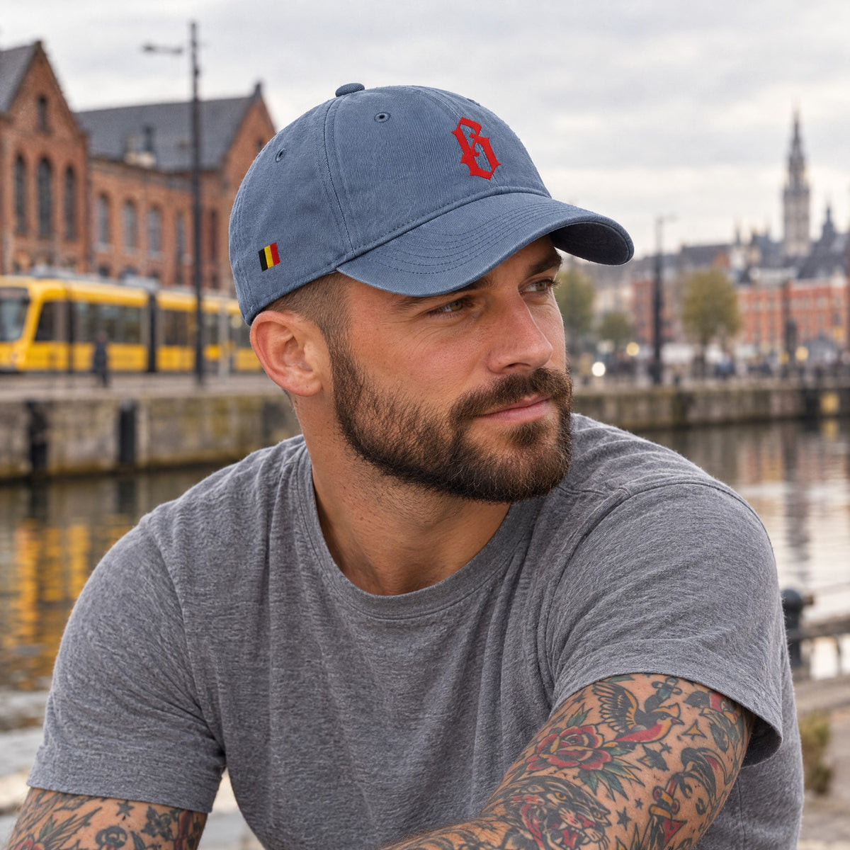 Casquette belge bleu jean brodée B rouge portée par un homme le long d'un canal à Bruxelles