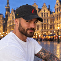 Casquette belge originale brodée B rouge, coloris noir, portée par un homme sur la Grand-Place de Bruxelles
