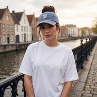 Casquette délavée dad cap vintage bleu jean portée par une femme sur un pont de canal belge