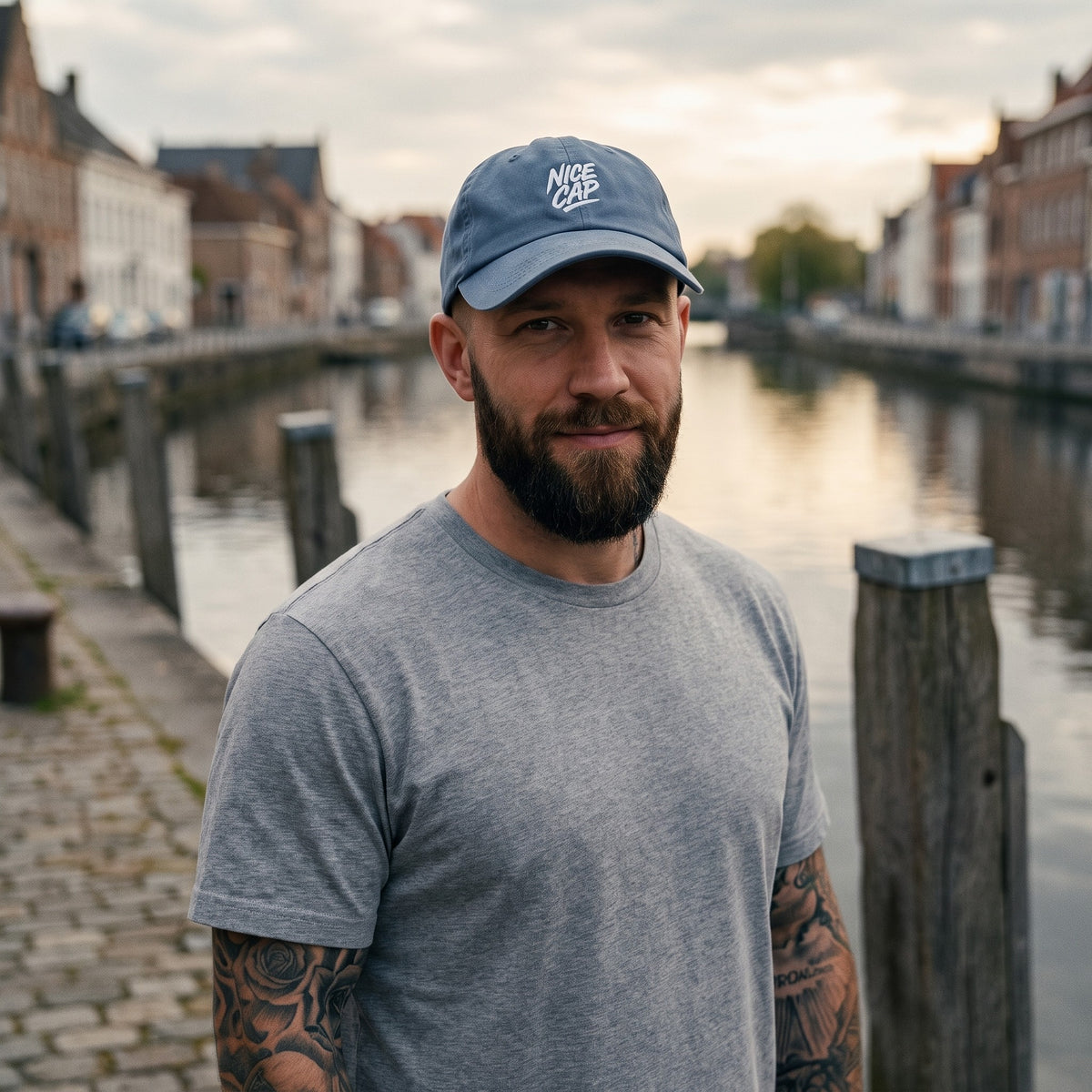 Casquette délavée dad cap vintage bleu jean portée par un homme sur un quai de canal belge