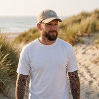 Casquette délavée dad cap vintage sable portée par un homme dans les dunes de la côte belge