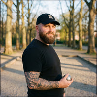 Homme portant la casquette de pétanque originale Boule King noire sur un terrain de pétanque