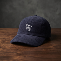 Casquette poker « Paire d'As » bleu marine en velours côtelé, as de pique et as de cœur brodés, posée sur bois foncé