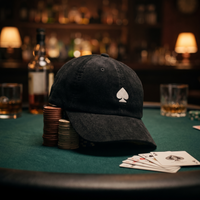 Casquette poker « Pique Blanc » posée sur une table de poker avec jetons et cartes