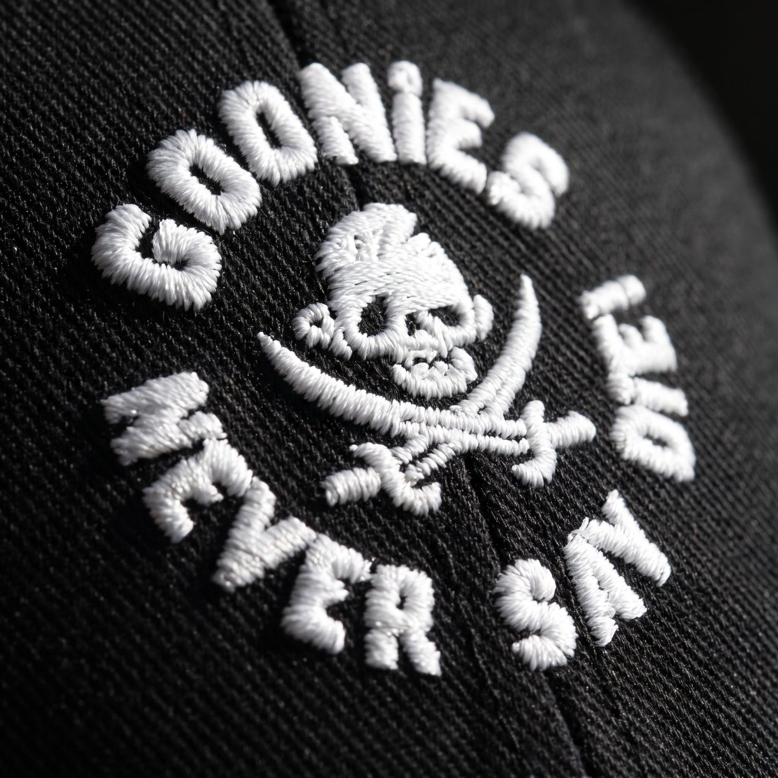 Macro de la broderie blanche Never Say Die sur la casquette Goonies noire