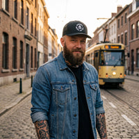 Casquette trucker Goonies noire portée par un homme dans une rue belge, style streetwear