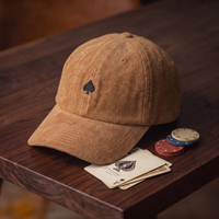 Casquette As de Pic Façade camel en velours côtelé, mise en scène avec cartes à jouer vintage et jetons de poker sur bois de noyer foncé