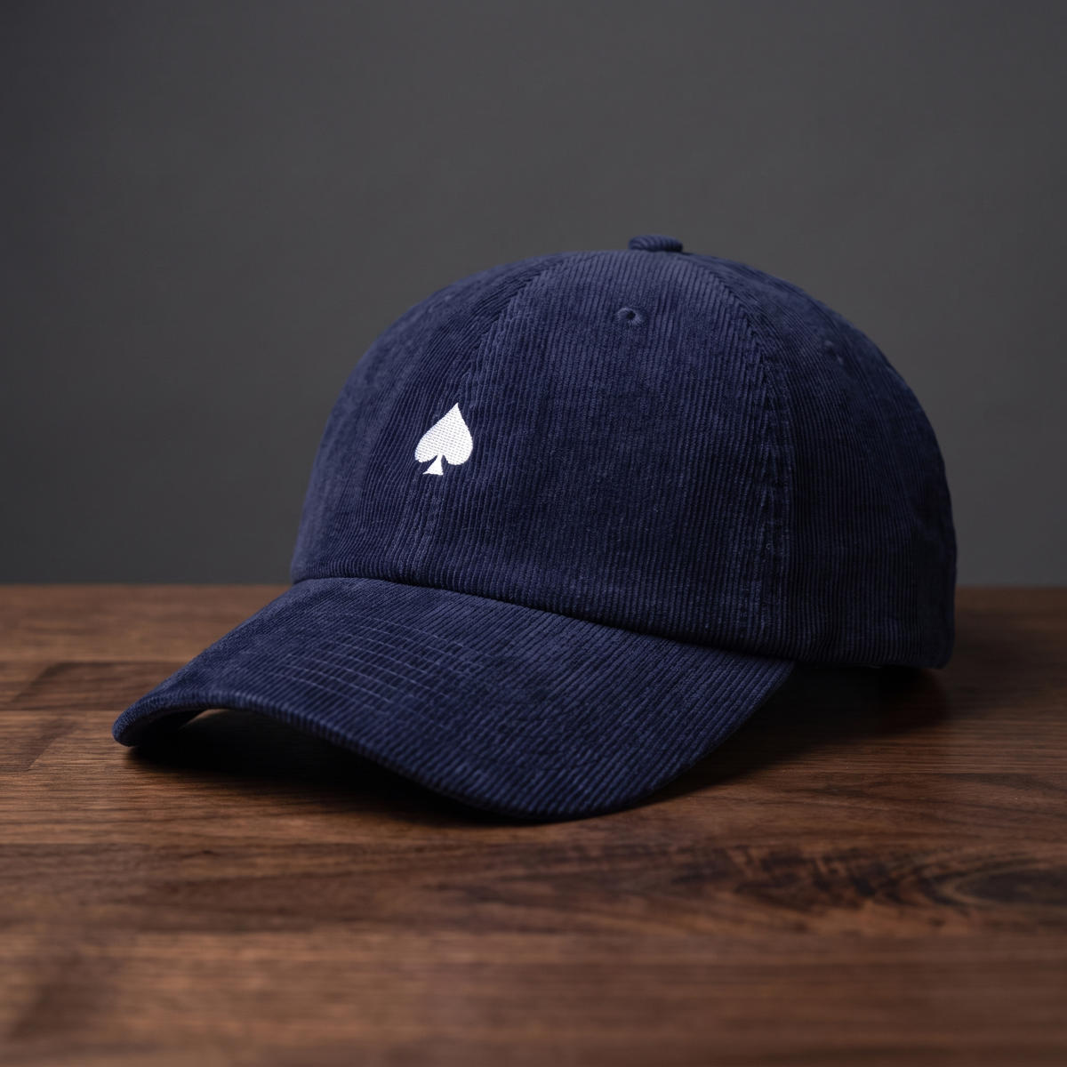 Casquette poker en velours côtelé bleu marine As de Pic - vue de profil trois-quarts sur fond bois et charbon