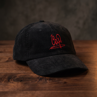 Casquette en velours côtelé noire brodée Cap, CHT'M Boutique, vue légèrement de trois-quarts sur bois de noyer foncé