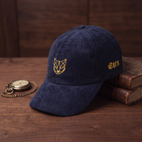 Casquette en velours côtelé CHT'M motif chat géométrique doré, couleur bleu marine, mise en scène avec montre à gousset et livres anciens