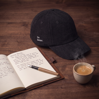 Casquette en velours côtelé noire CHT'M "Do Better." mise en scène avec carnet, stylo et tasse de café