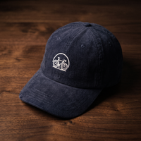 Casquette en velours côtelé bleu marine brodée vélo, CHT'M Boutique, vue légèrement de trois-quarts sur bois de noyer foncé