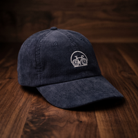 Casquette en velours côtelé bleu marine brodée vélo, CHT'M Boutique, vue prononcée de trois-quarts sur bois de noyer foncé
