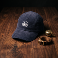Casquette en velours côtelé bleu marine brodée vélo, CHT'M Boutique, mise en scène cloche de vélo et lanière en cuir sur bois de noyer foncé