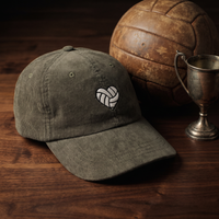 Casquette en velours côtelé olive CHT'M Boutique avec broderie cœur ballon de volley - mise en scène ballon de volley en cuir et trophée bois noyer foncé