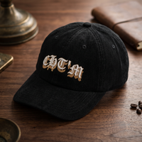 Casquette en velours côtelé noire CHT'M brodée du motif gothique « CHT'M », vue trois-quarts prononcée, sur fond bois noyer foncé