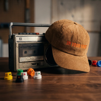 Casquette en velours côtelé camel CHT'M Boutique en situation, broderie orange 'In Your Face' — casquette streetwear belge