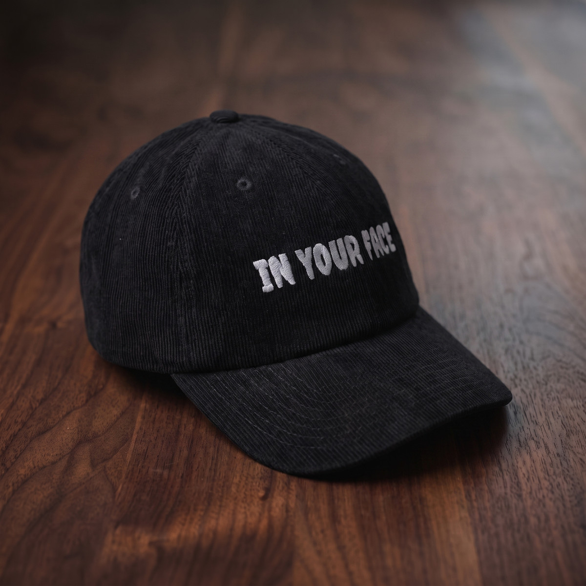 Casquette en velours côtelé noire CHT'M Boutique avec broderie grise 'In Your Face' — casquette streetwear belge, vue d'angle