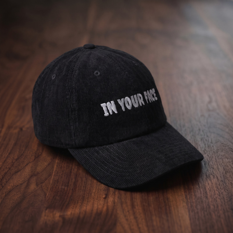 Casquette en velours côtelé noire CHT'M Boutique avec broderie grise 'In Your Face' — casquette streetwear belge, vue d'angle