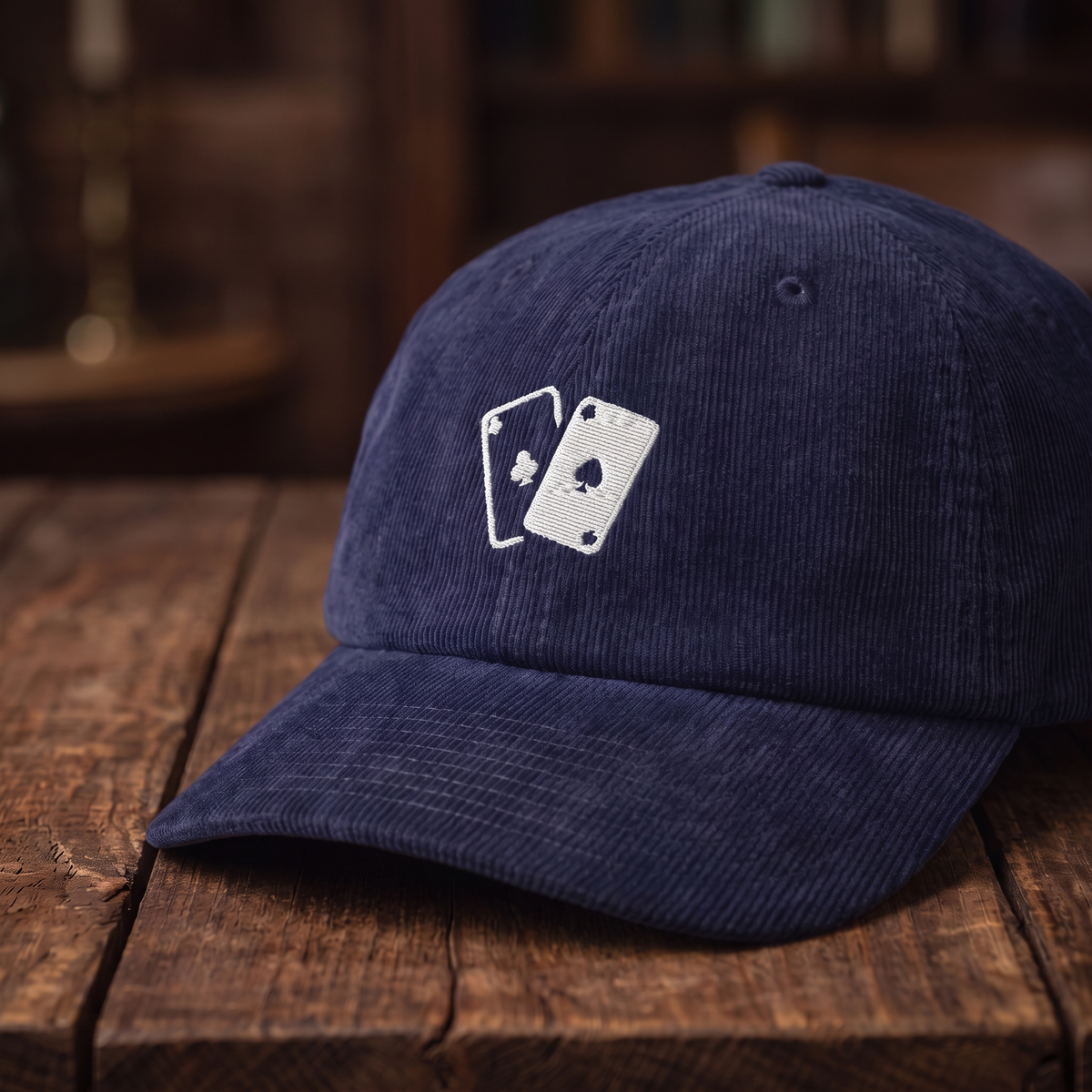 Casquette en velours côtelé motif jeu de cartes, coloris bleu marine oxford, vue trois-quarts rapprochée sur fond bois noyer foncé
